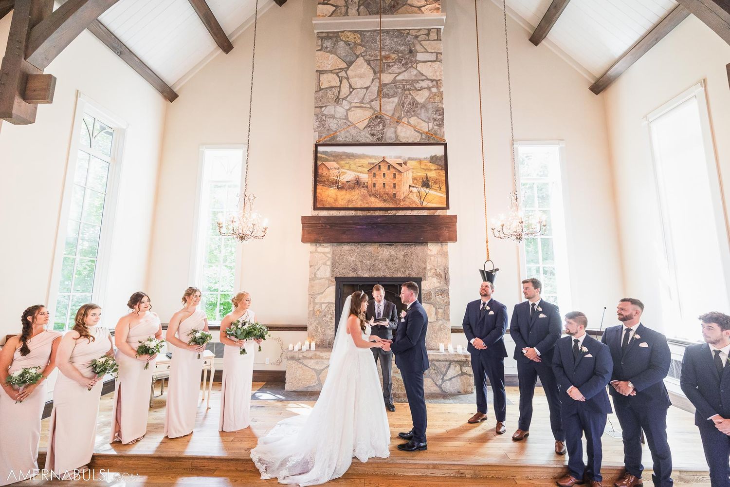 Wedding ceremony in rustic chapel with stone fireplace and exposed wooden beams.