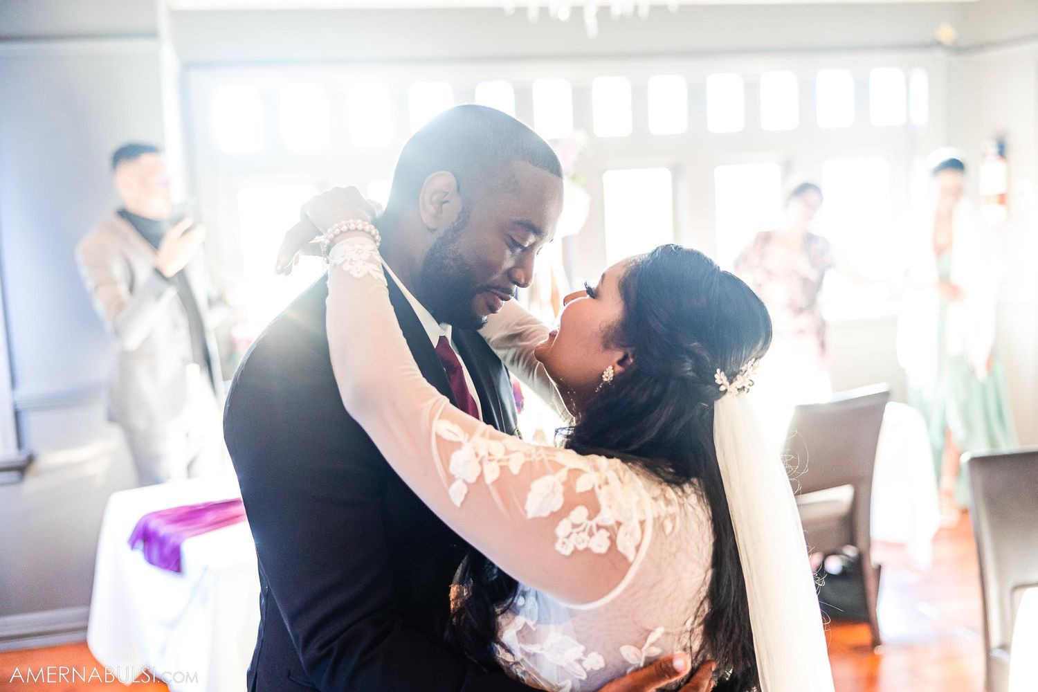 An intimate moment during a wedding first dance in a sunlit reception hall.