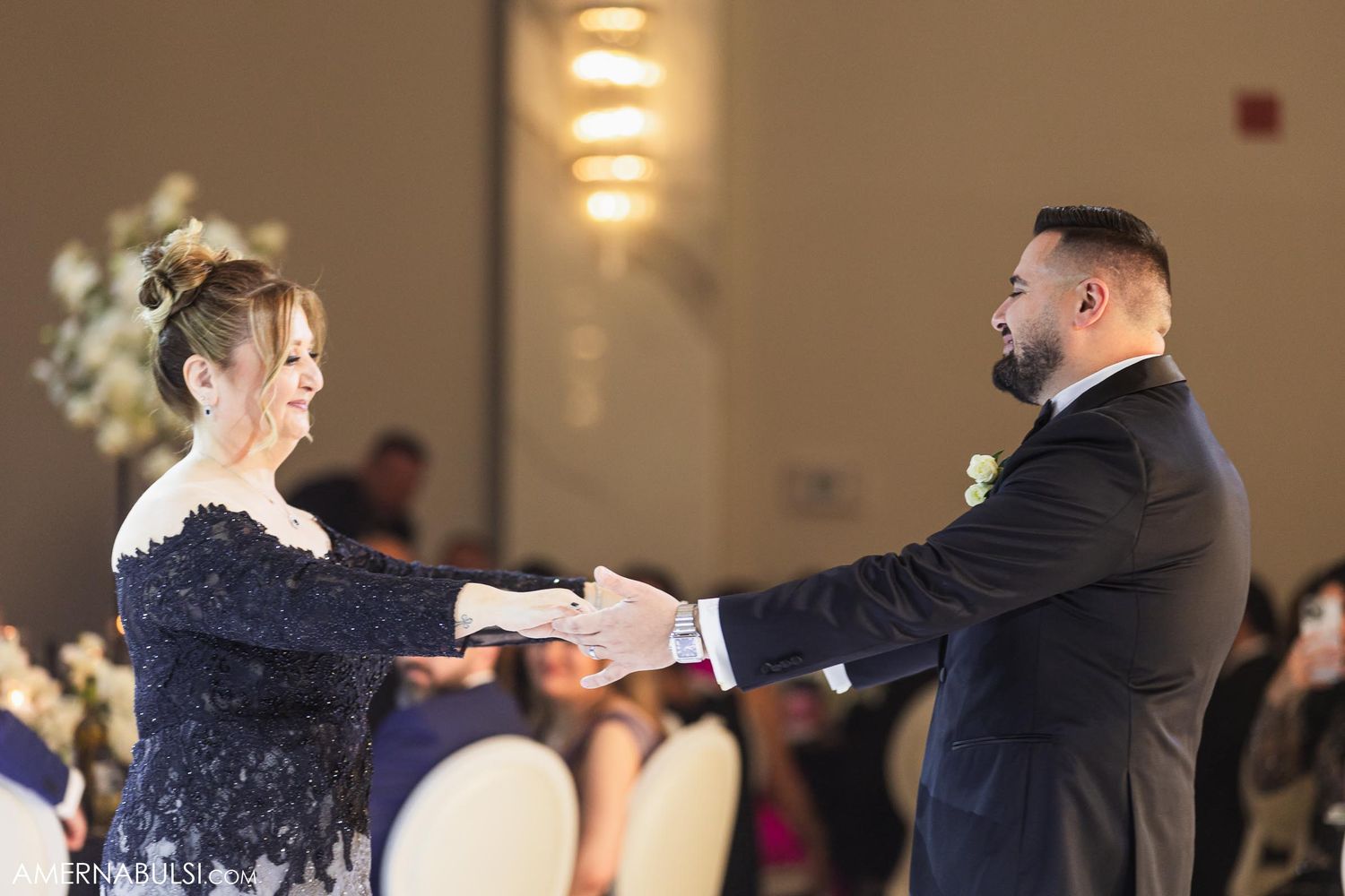 Elegantly dressed couple performs traditional dance at wedding reception.