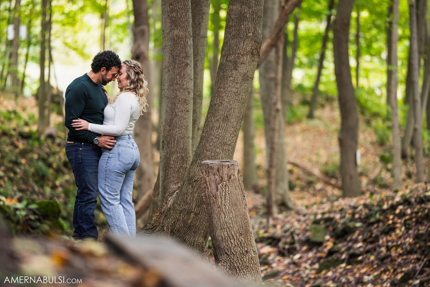 A couple shares a quiet moment together on a leaf-covered forest path.