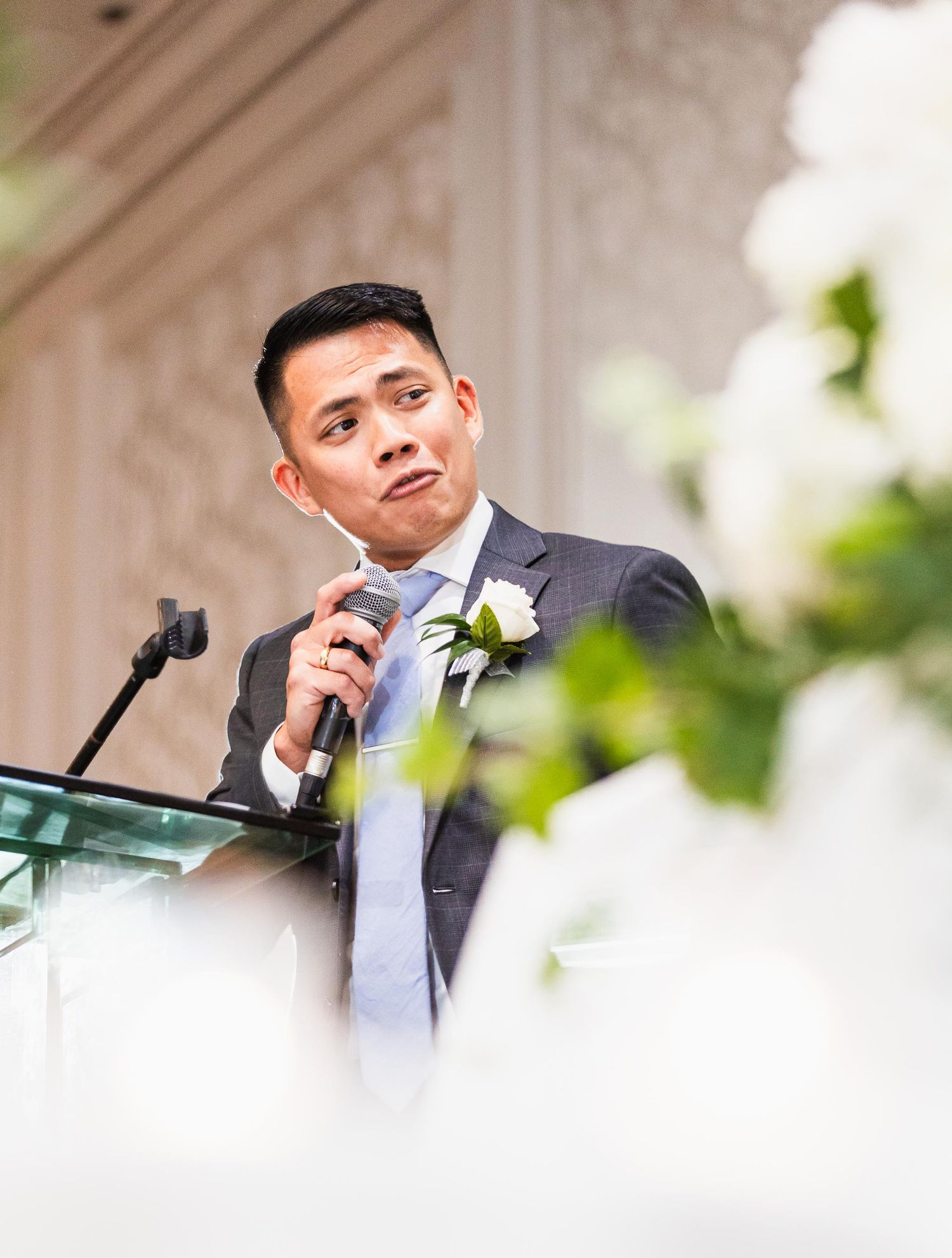 Best man gives emotional wedding speech at elegant reception podium.