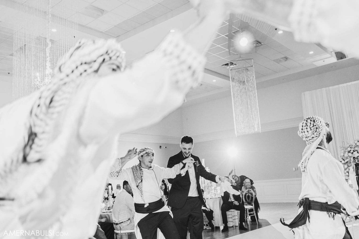 Black and white photo of wedding guests dancing with fabric flowing through the air.