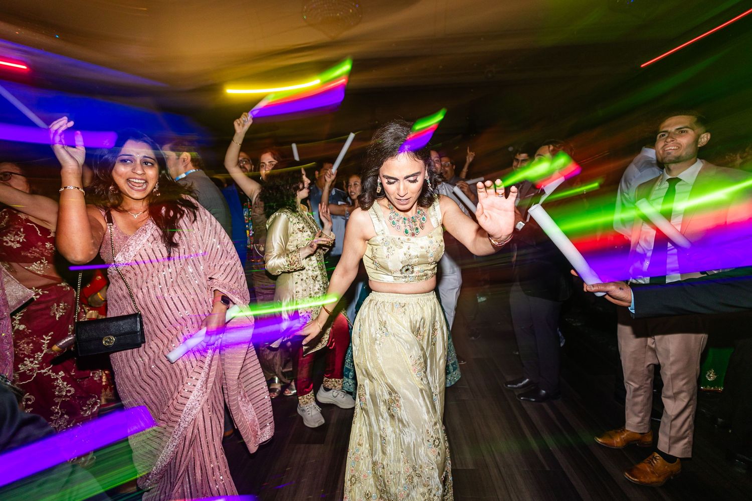 People dancing and celebrating at a nightclub with colorful lighting and disco atmosphere.