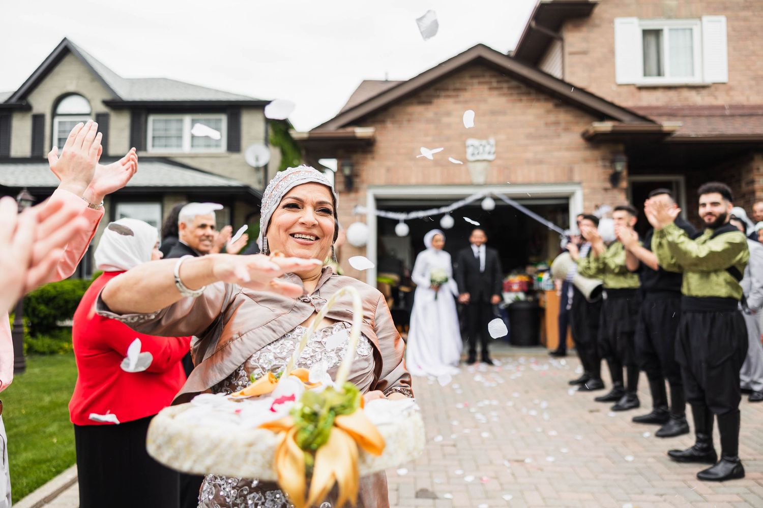 Wedding guests throw confetti during celebrations outside a brick venue with white lanterns.