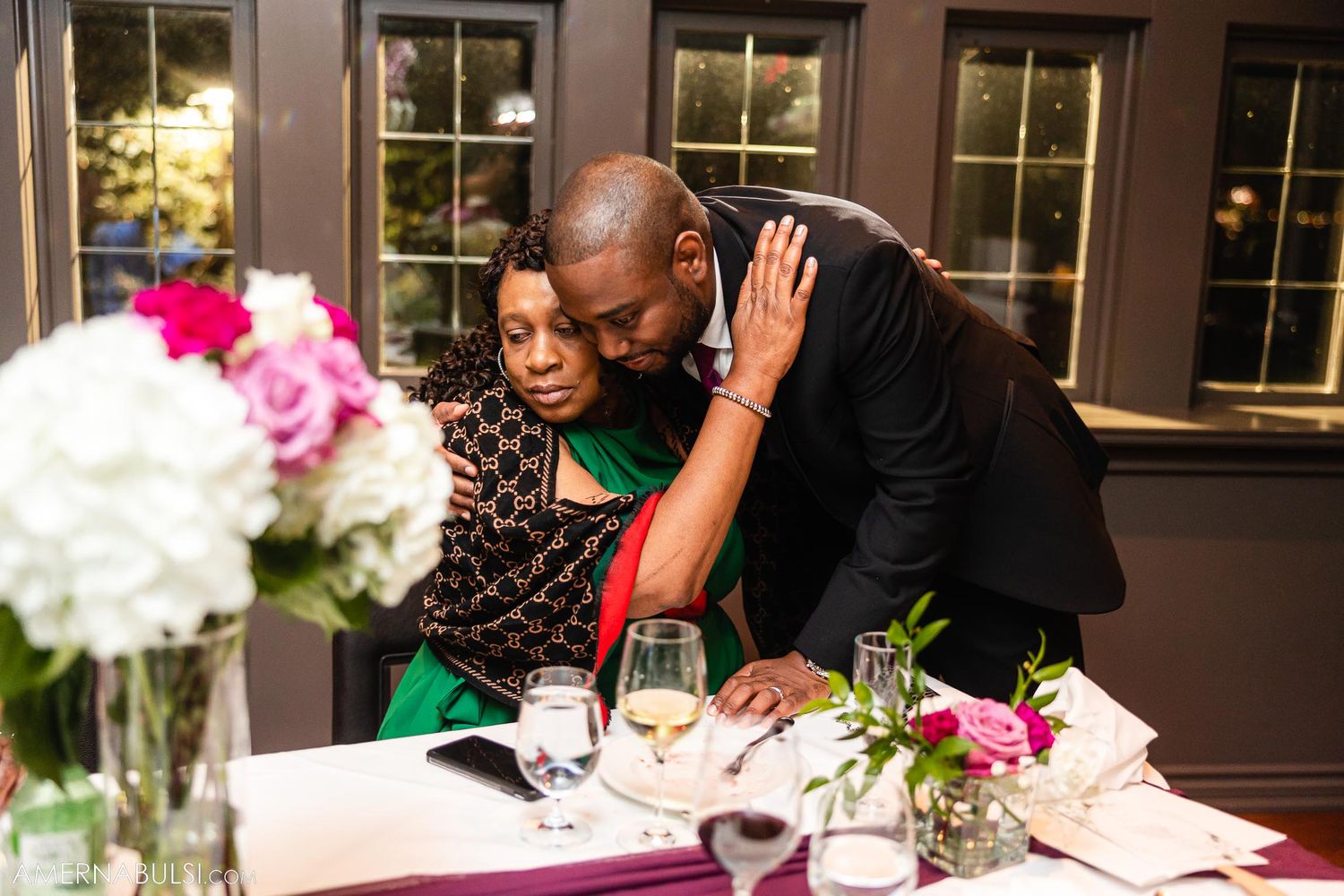 Tender moment between couple at elegant dinner reception with floral centerpiece.
