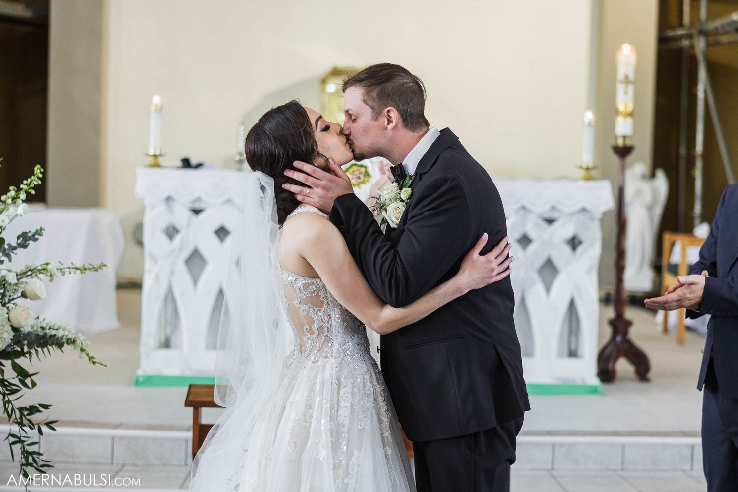 A couple shares their first kiss at the altar during a traditional church wedding ceremony.