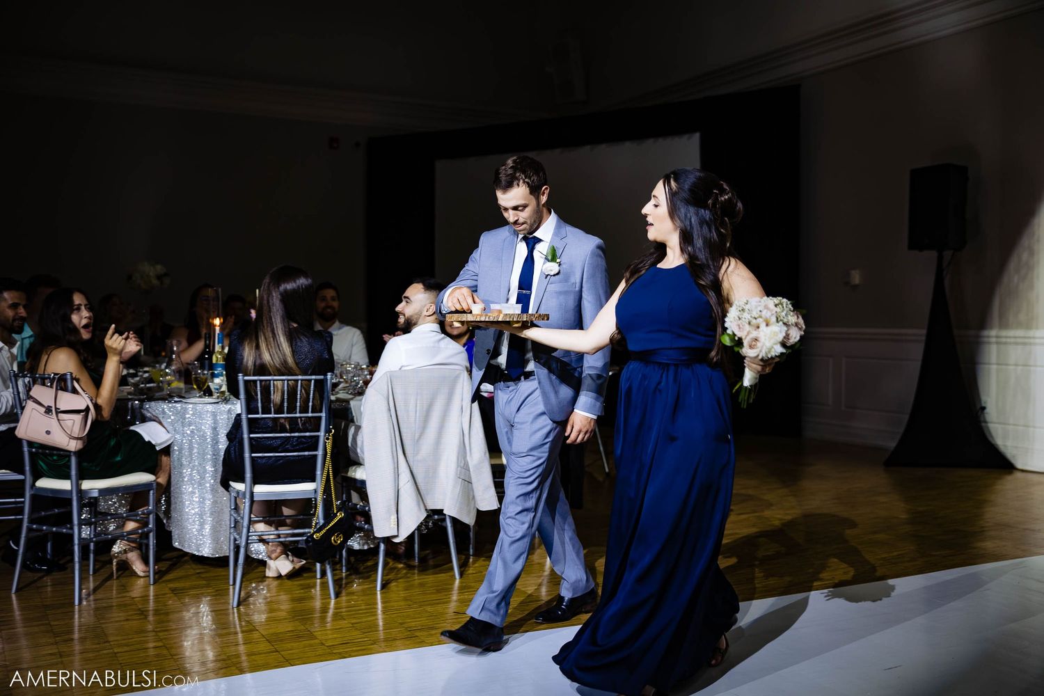 Formal reception gathering with attendants in navy and grey standing near seated guests.