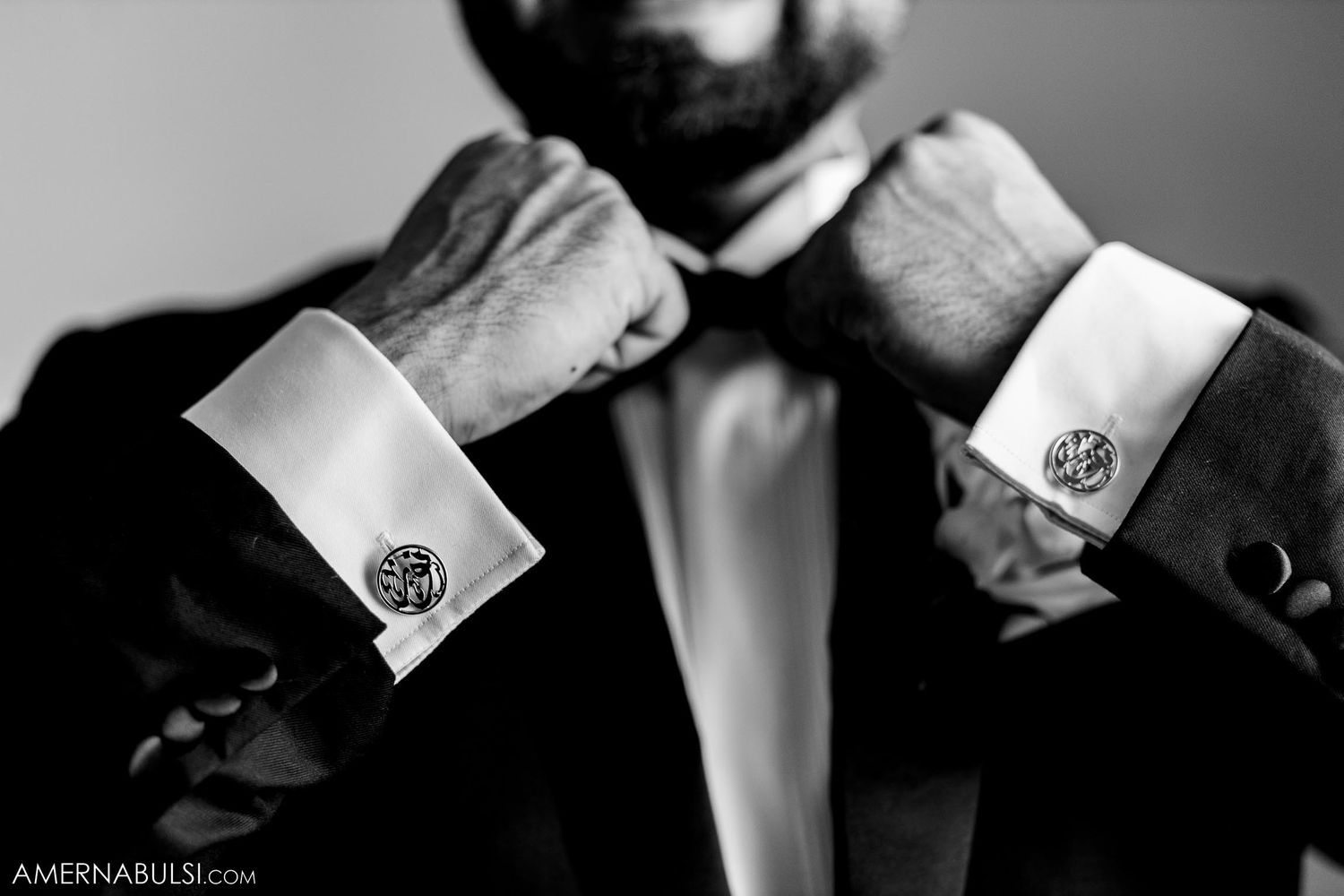 Black and white photo of hands adjusting formal cufflinks and bowtie.