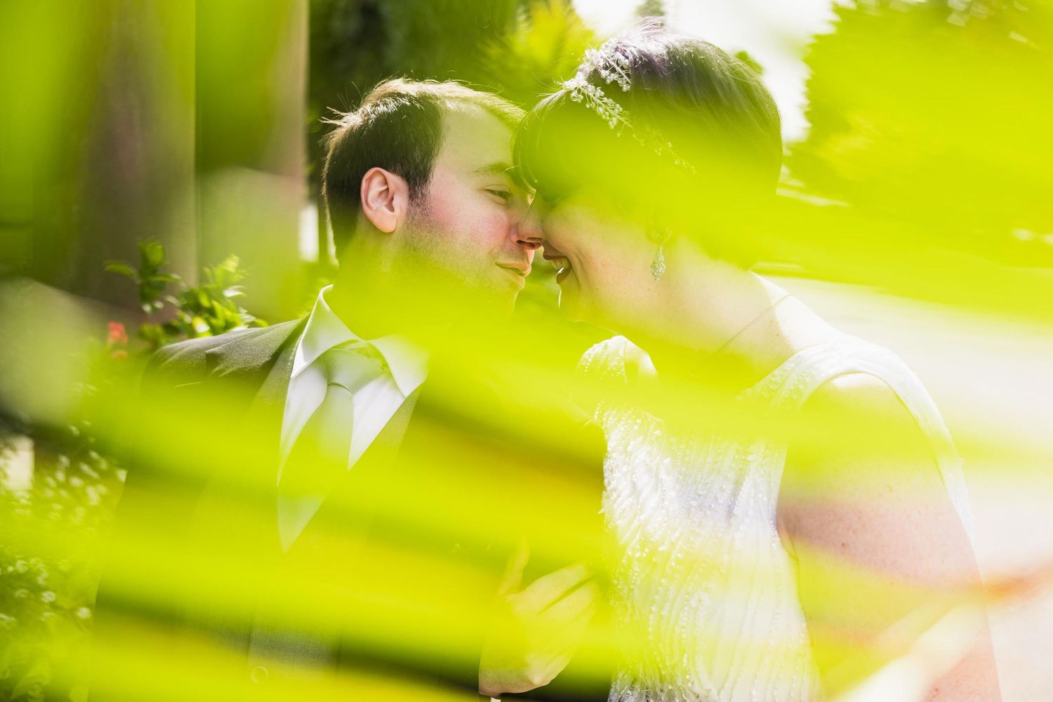 Intimate portrait through green foliage with soft natural lighting.