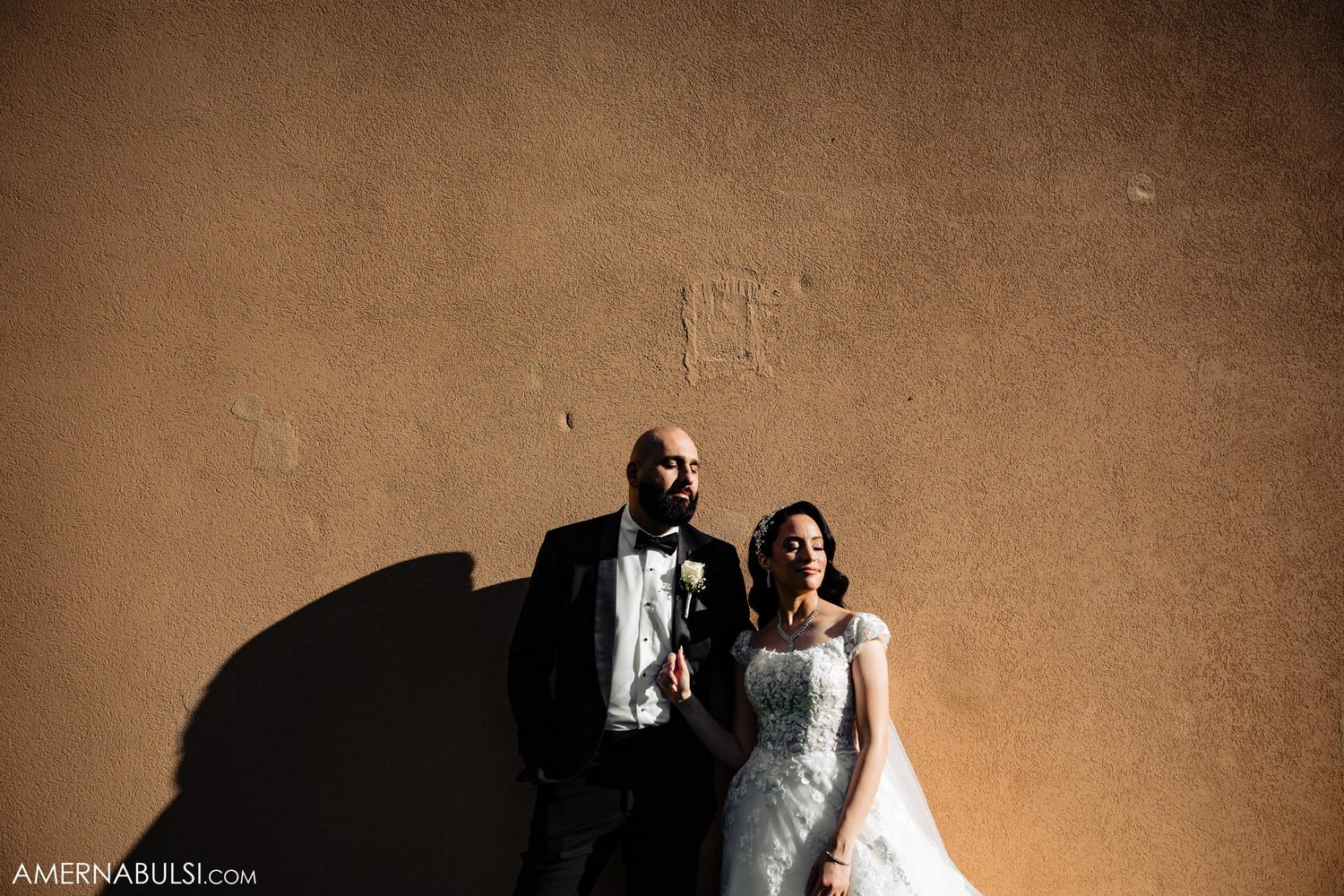 Artistic wedding portrait against textured wall in sepia tones.