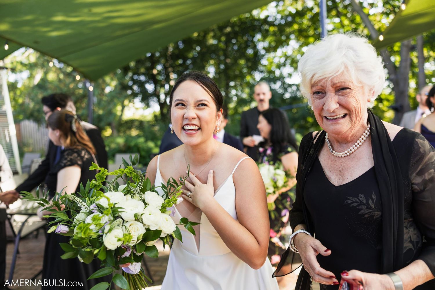 A joyful outdoor wedding celebration with white floral arrangements and natural greenery.