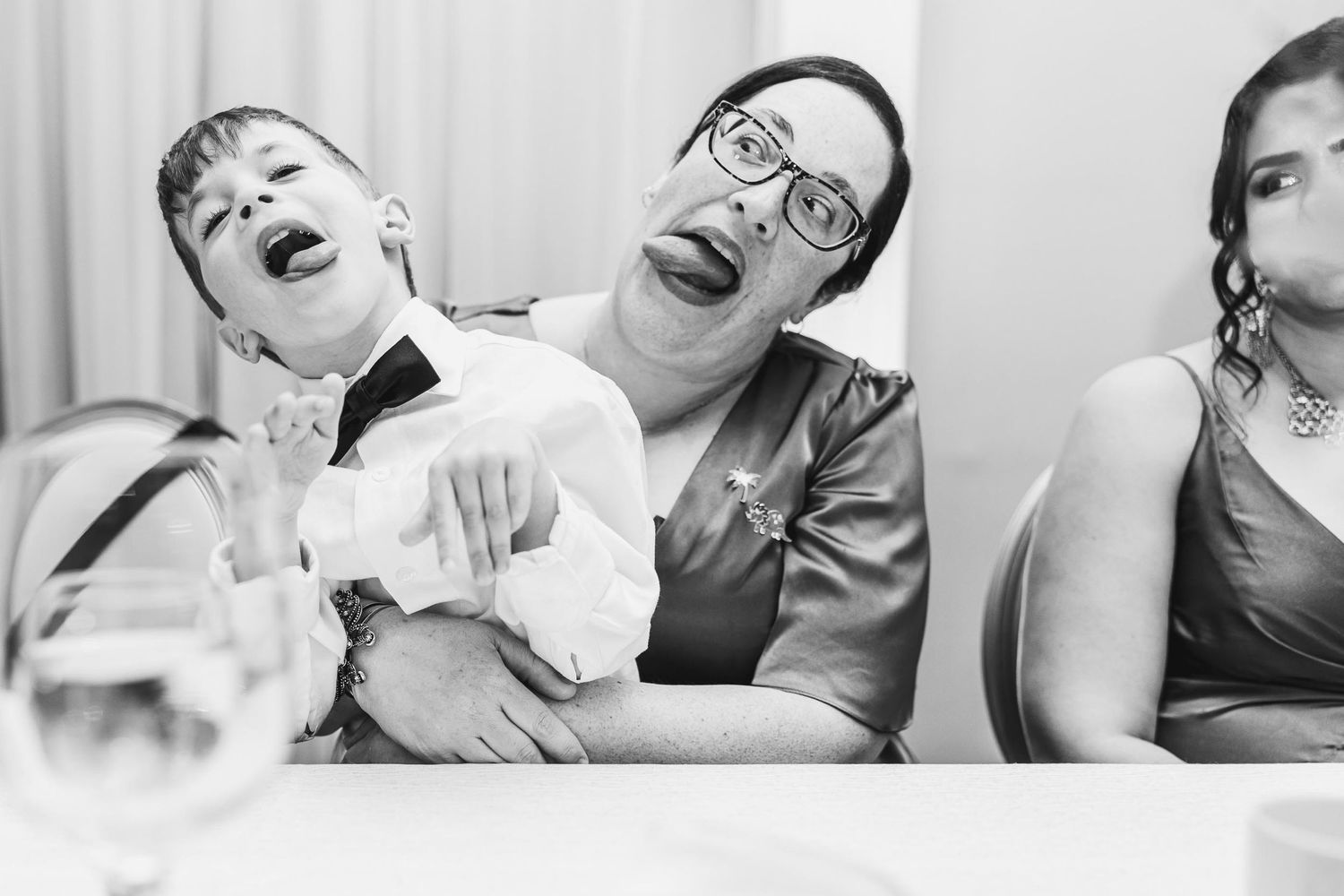 Candid black and white photo of guests laughing during a wedding reception.