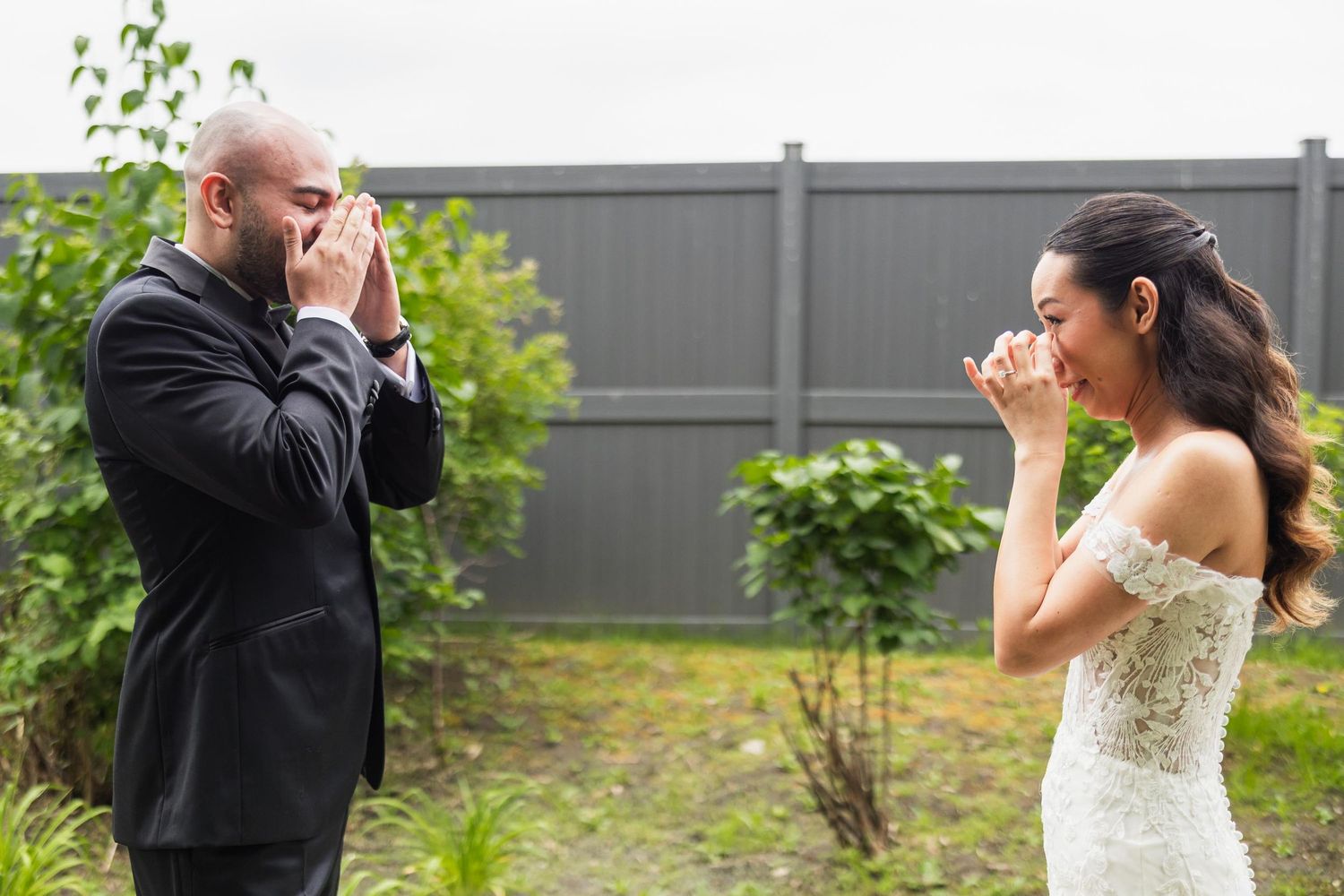 An emotional first look moment between a couple in wedding attire in a garden setting.