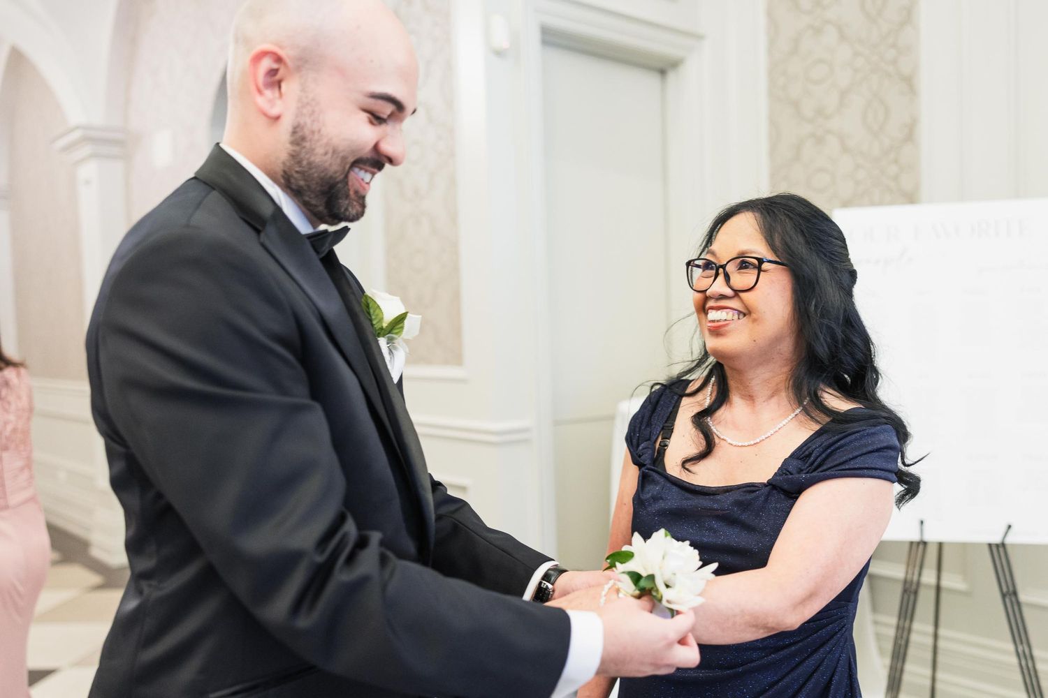 Couple exchanges corsage during indoor wedding ceremony.