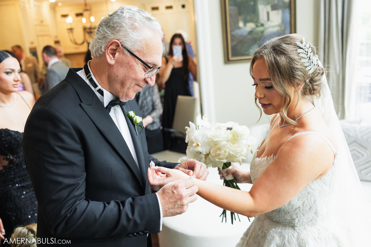 An emotional ring exchange moment during wedding preparations in a sunlit room.