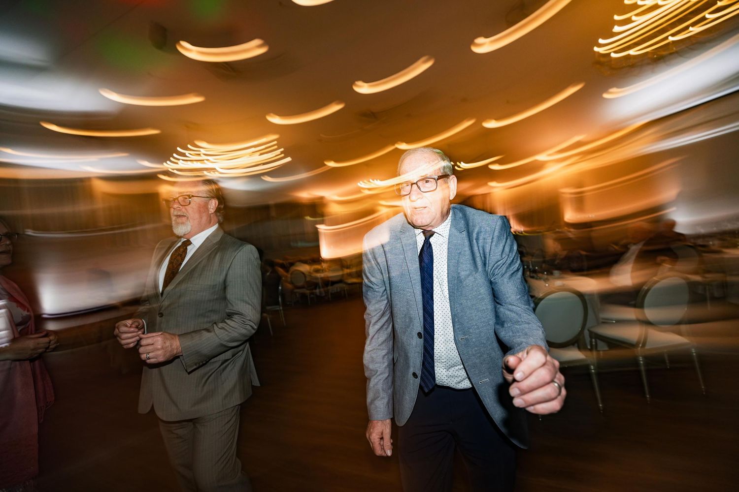 Motion blur capture of men walking through venue with warm lighting effects.