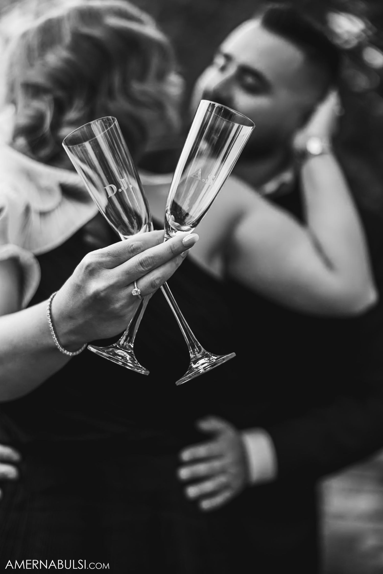 Two champagne flutes clink together in a romantic black and white moment.