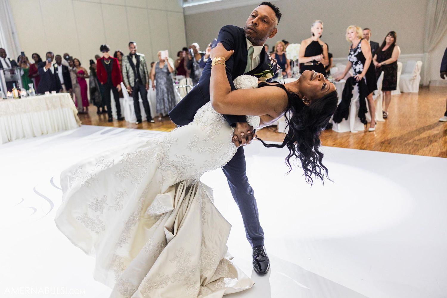 Dramatic dance dip during wedding reception on white dance floor.