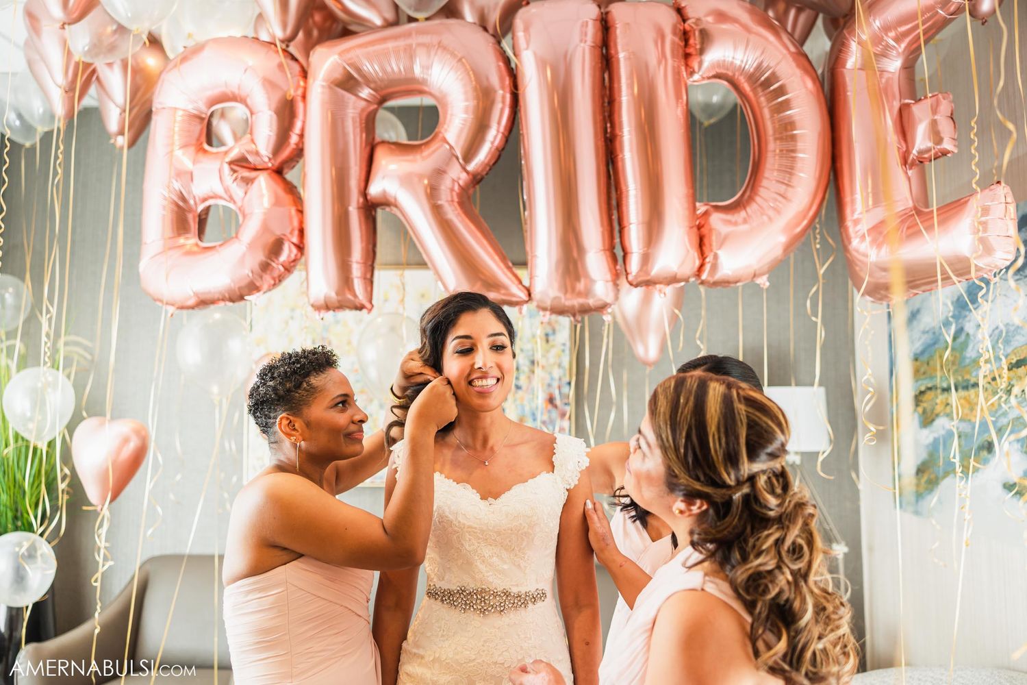 Rose gold BRIDE balloons decorate a bridal preparation scene with pink bridesmaids dresses.