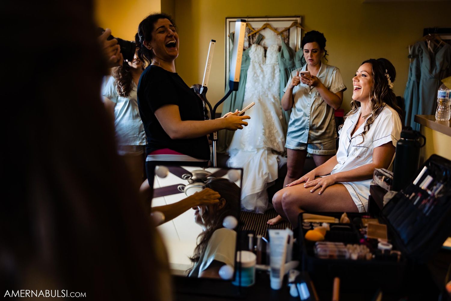 Wedding preparation scene with people in a room with dresses and camera equipment.