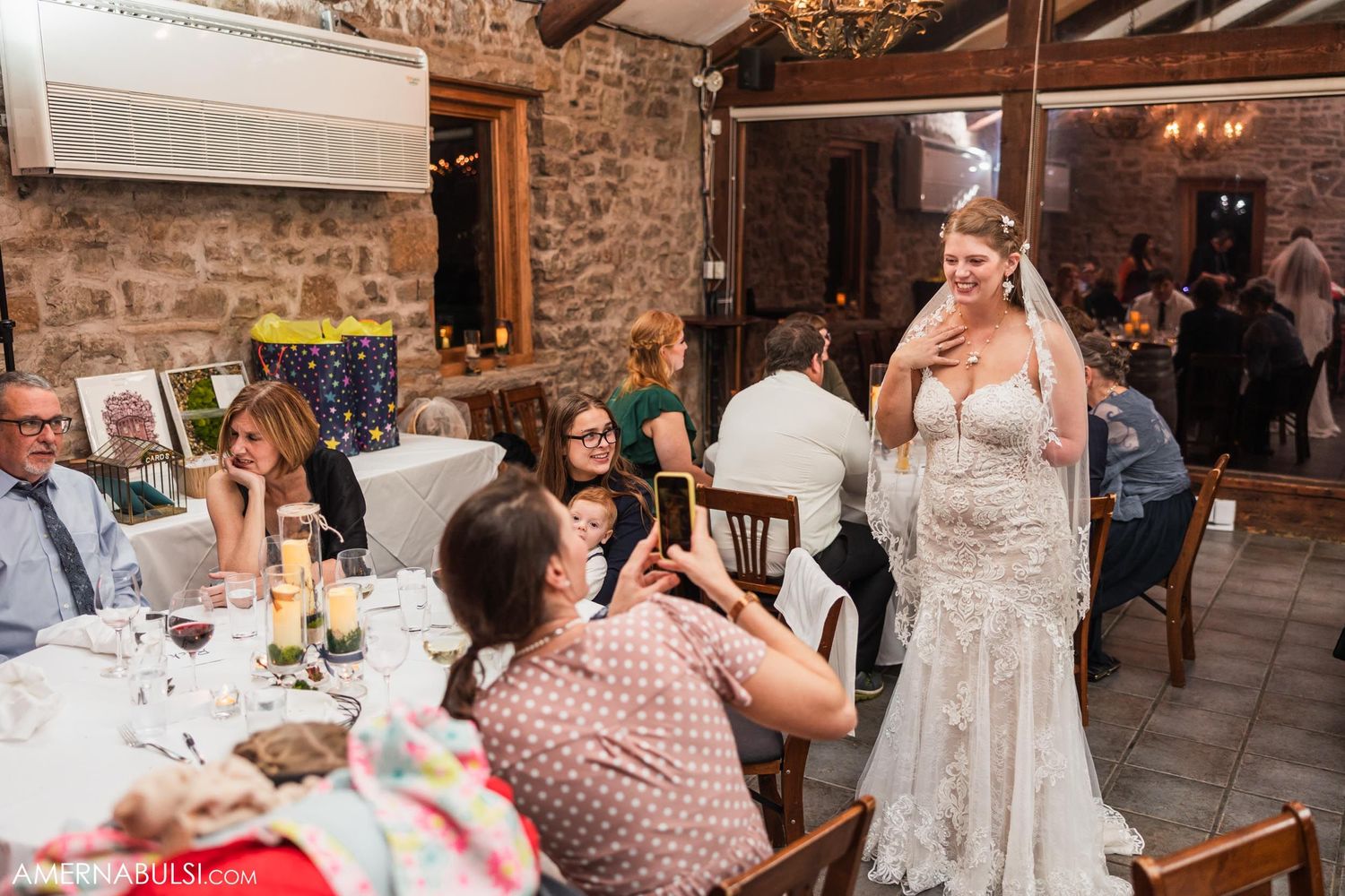 Wedding reception in rustic stone venue with elegant chandeliers and exposed beams.