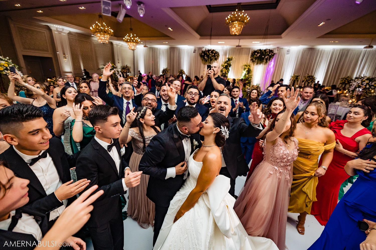 Jubilant wedding celebration showing a packed dance floor with guests in formal attire.