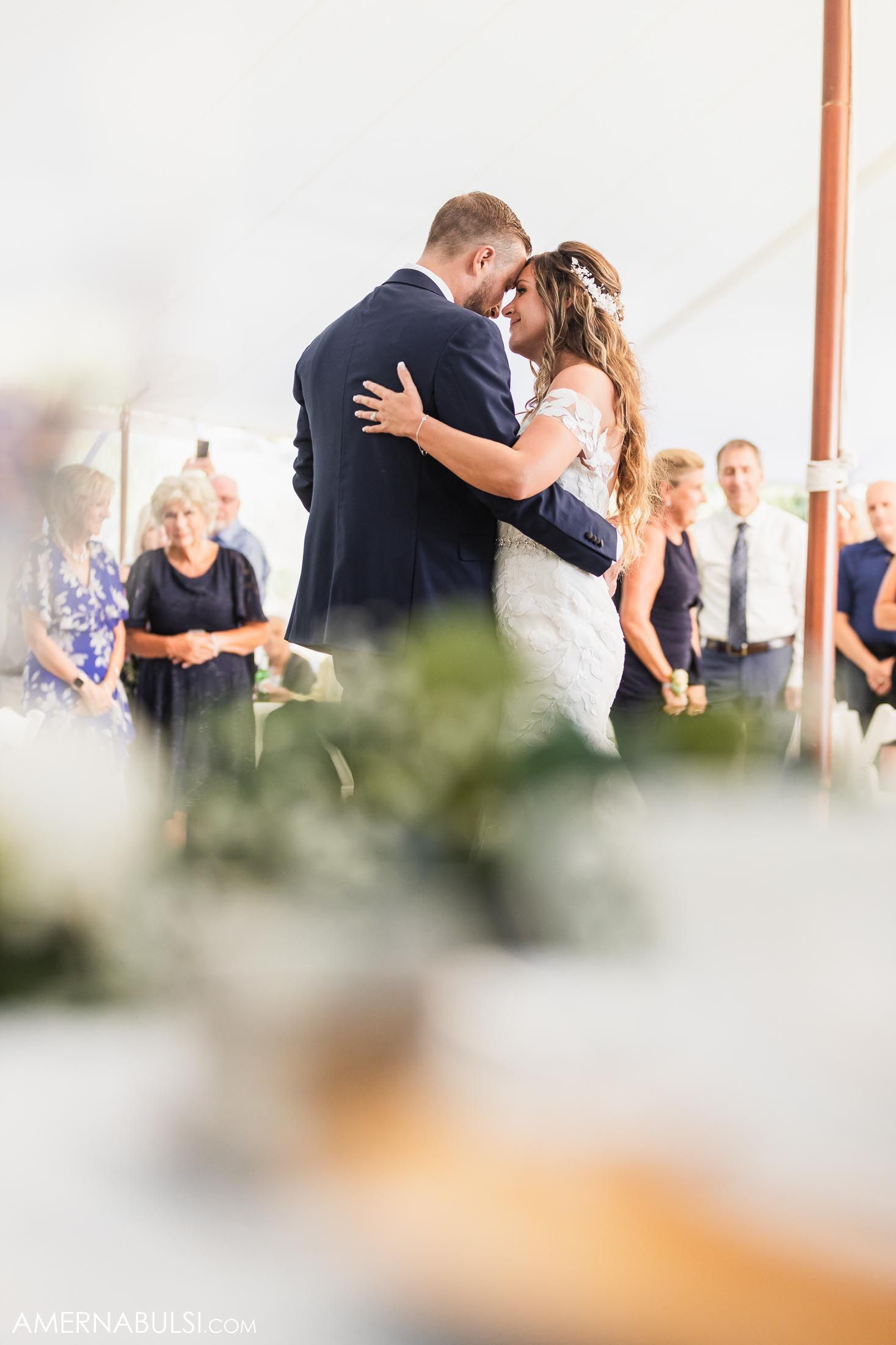 Couple shares playful moment at decorated head table during wedding reception.