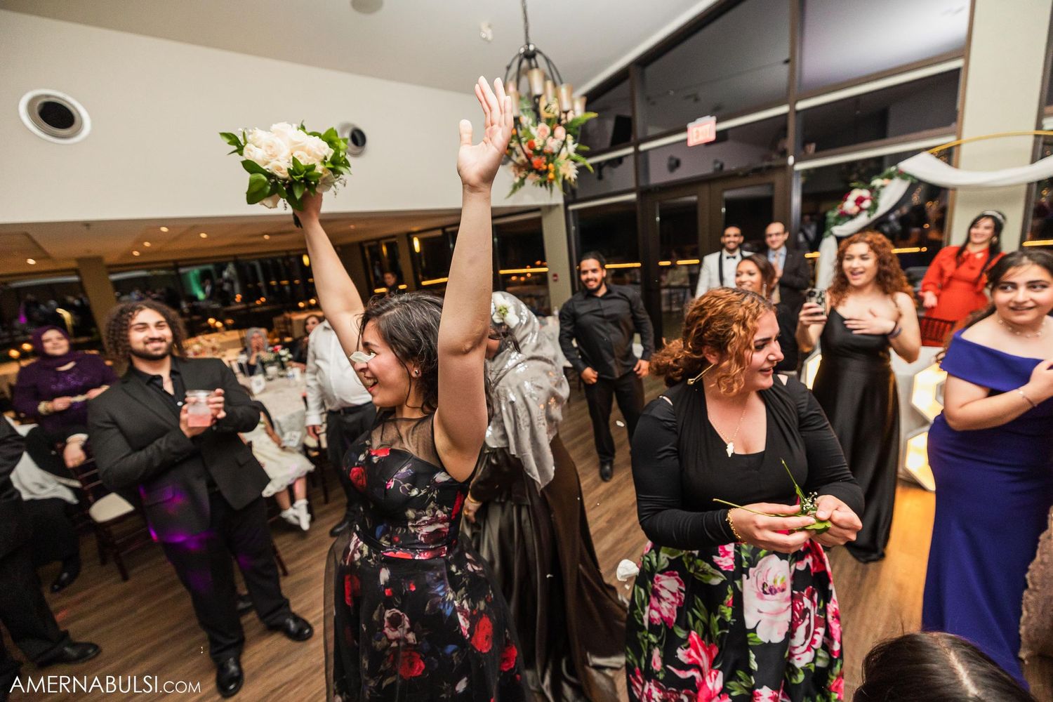Excited wedding guests celebrating and raising their hands during reception party.