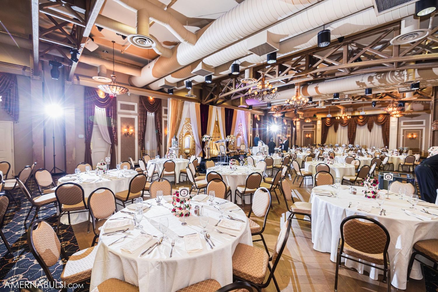 An elegant reception hall set up with round tables and white linens for a formal wedding celebration.