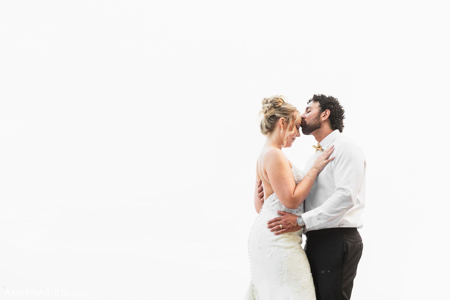 A romantic moment between newlyweds in a minimalist white setting.