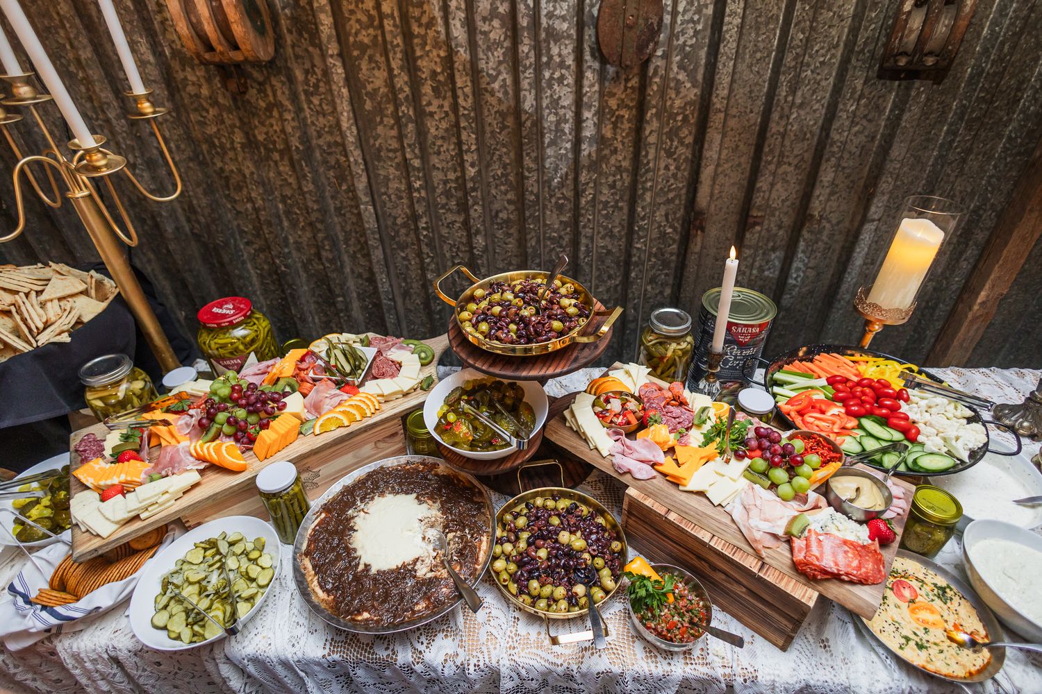 Elaborate wedding reception buffet table featuring various appetizers and dishes against rustic wood backdrop.