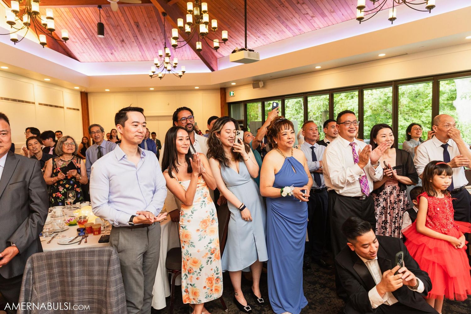 Wedding guests gather to watch special moments during indoor reception celebration.