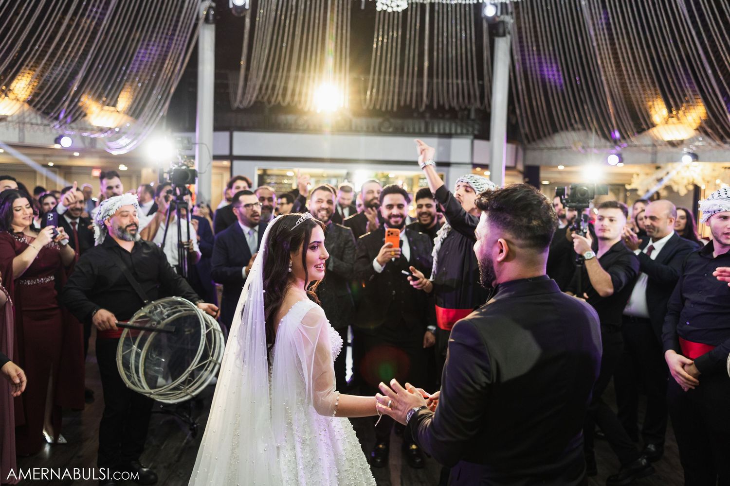 Wedding venue decorated with dramatic lighting and elegant white floral arrangements.