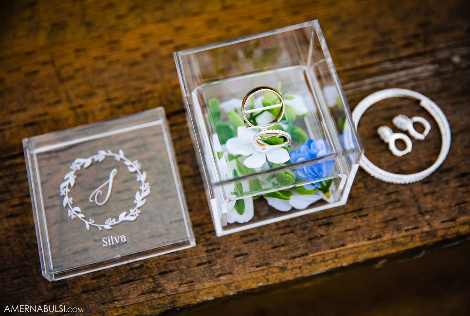 Clear acrylic wedding favor boxes with monogram and logo details displayed on wooden surface.