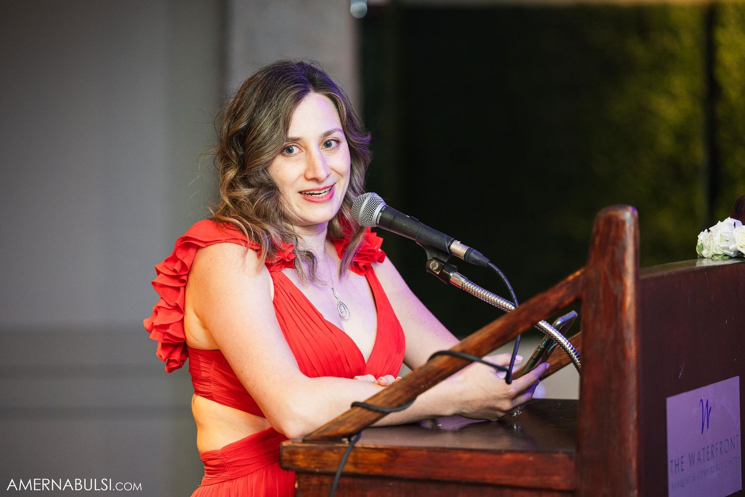 Wedding speech being delivered at podium by speaker wearing red dress.