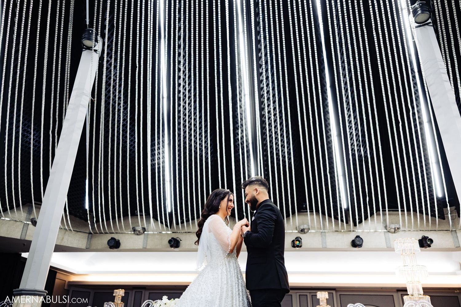 Wedding couple poses beneath modern white striped architectural ceiling design.