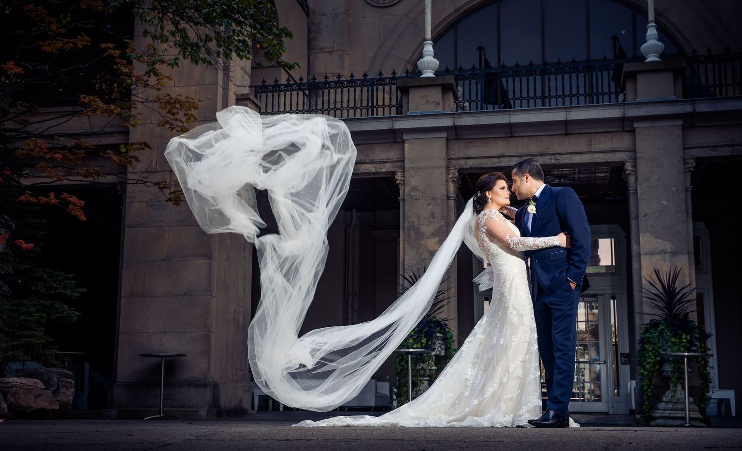 Dramatic wedding photos with flowing veil against urban architecture.