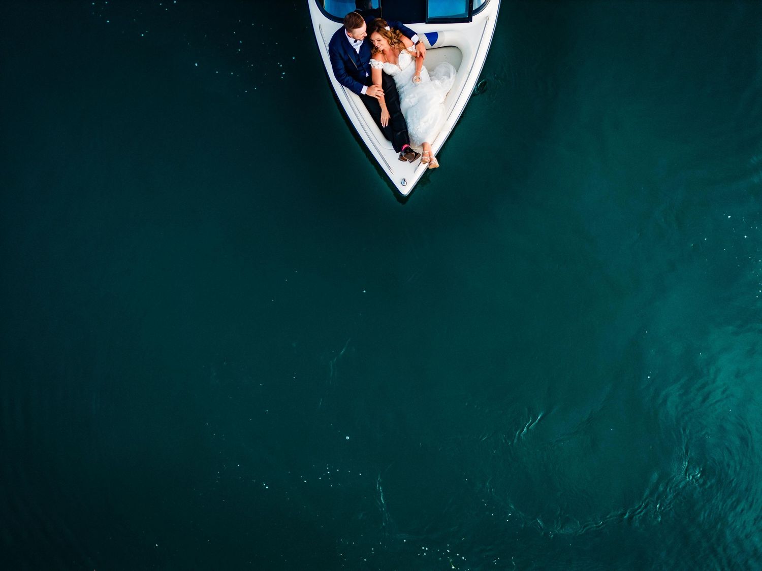 Aerial drone shot captures couple on a dark teal background creating geometric patterns.