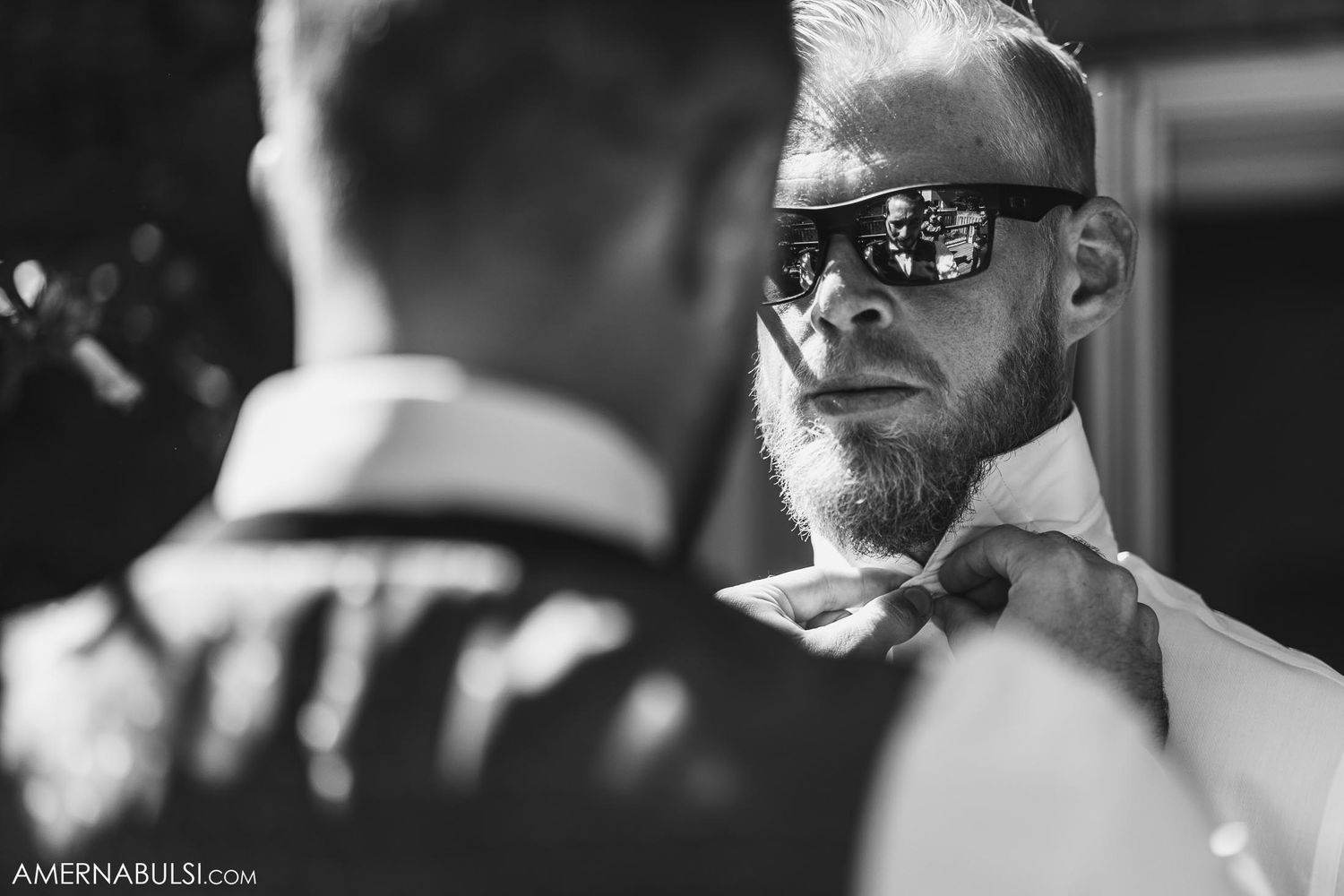 Black and white image of a person wearing sunglasses during wedding preparations.
