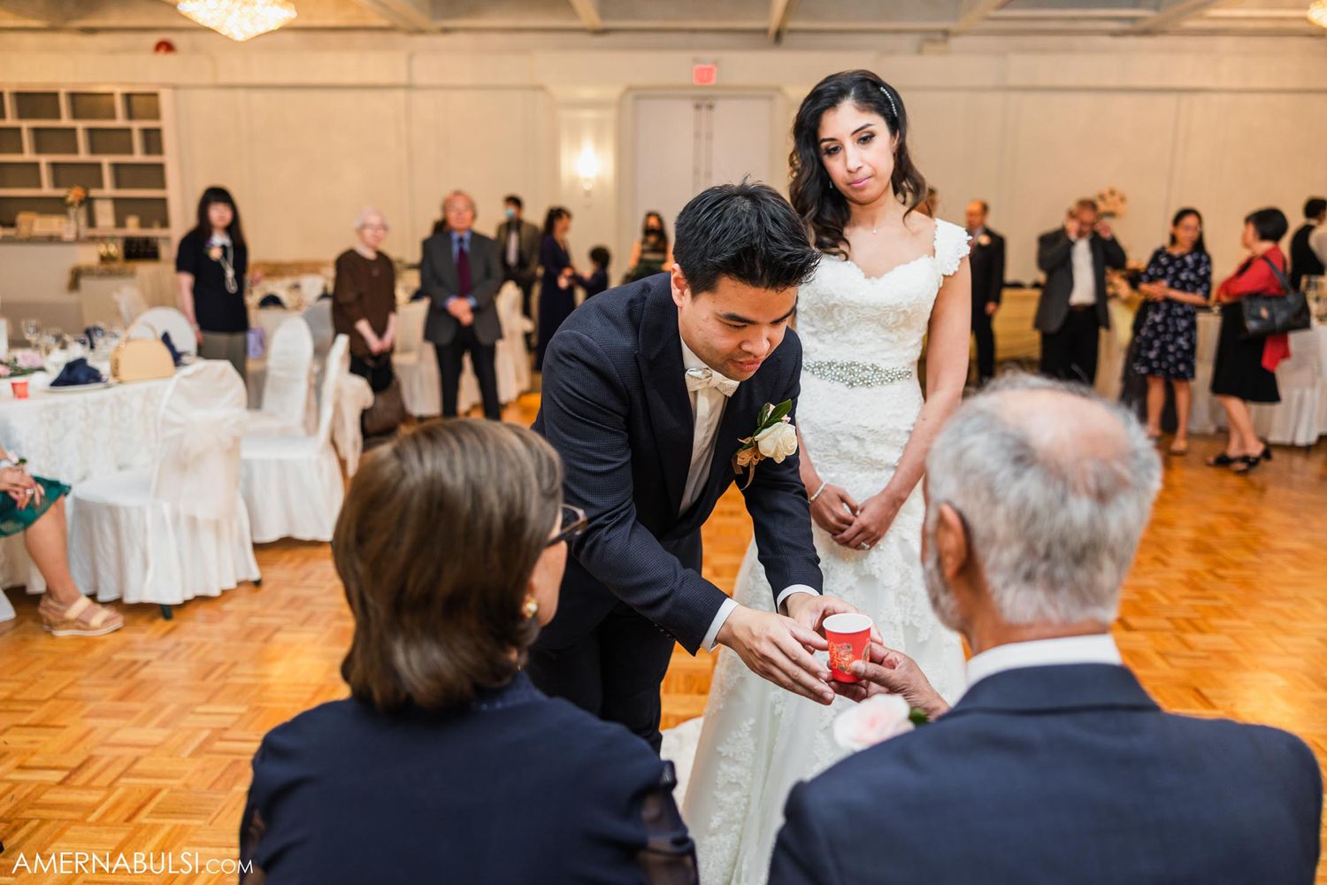 Wedding reception scene with couple greeting guests in a banquet hall with hardwood floors.