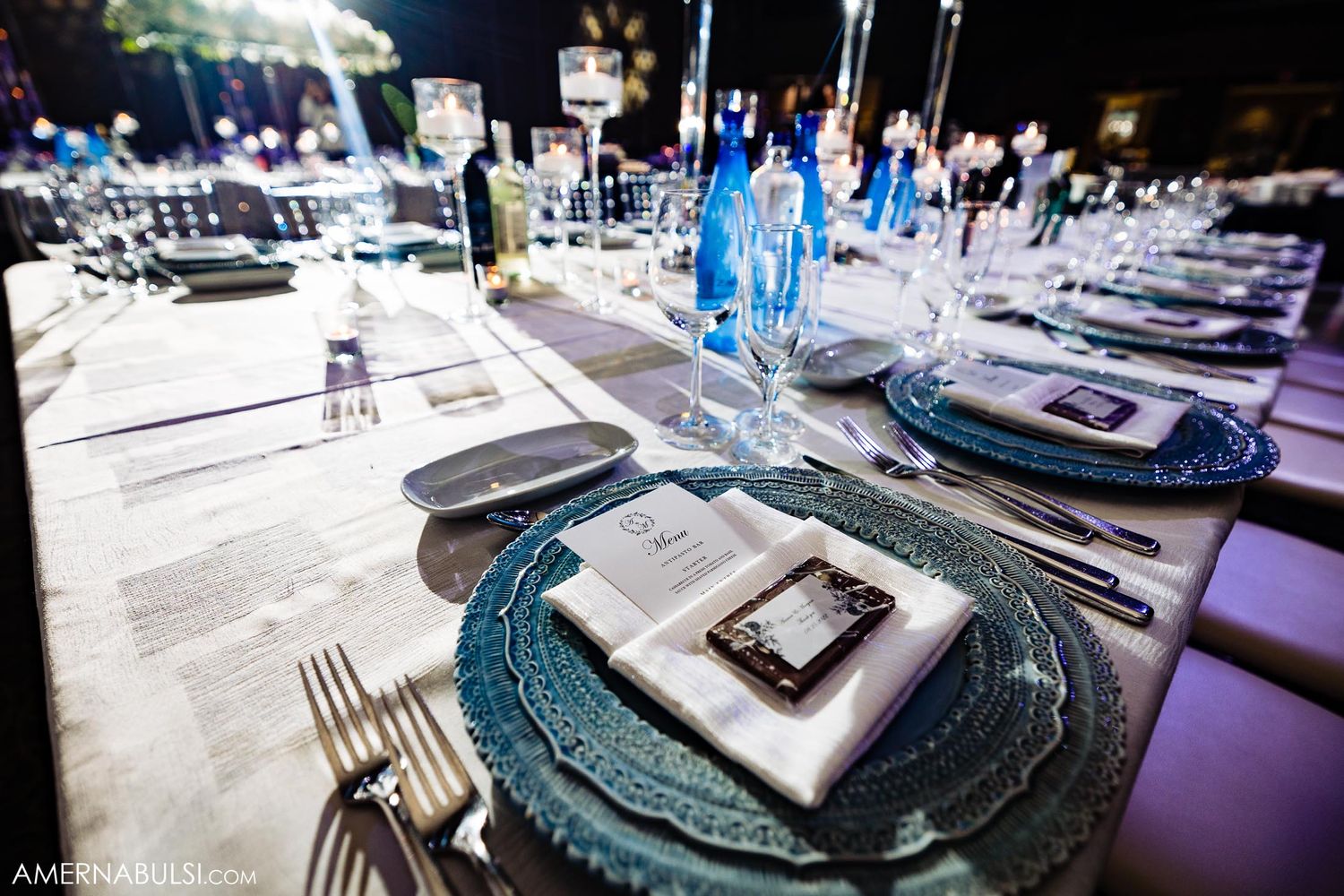 Elegant wedding table setting with turquoise charger plates and crystal glassware.