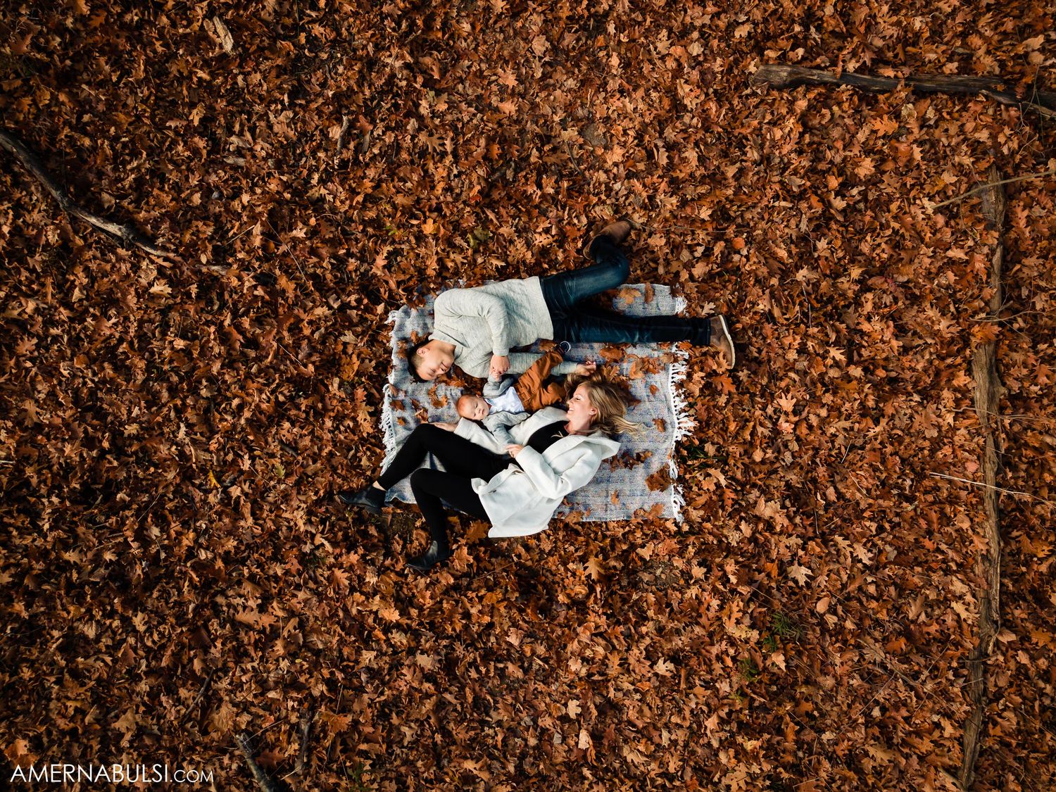 Aerial view of people lying on autumn leaves creating a circular composition.