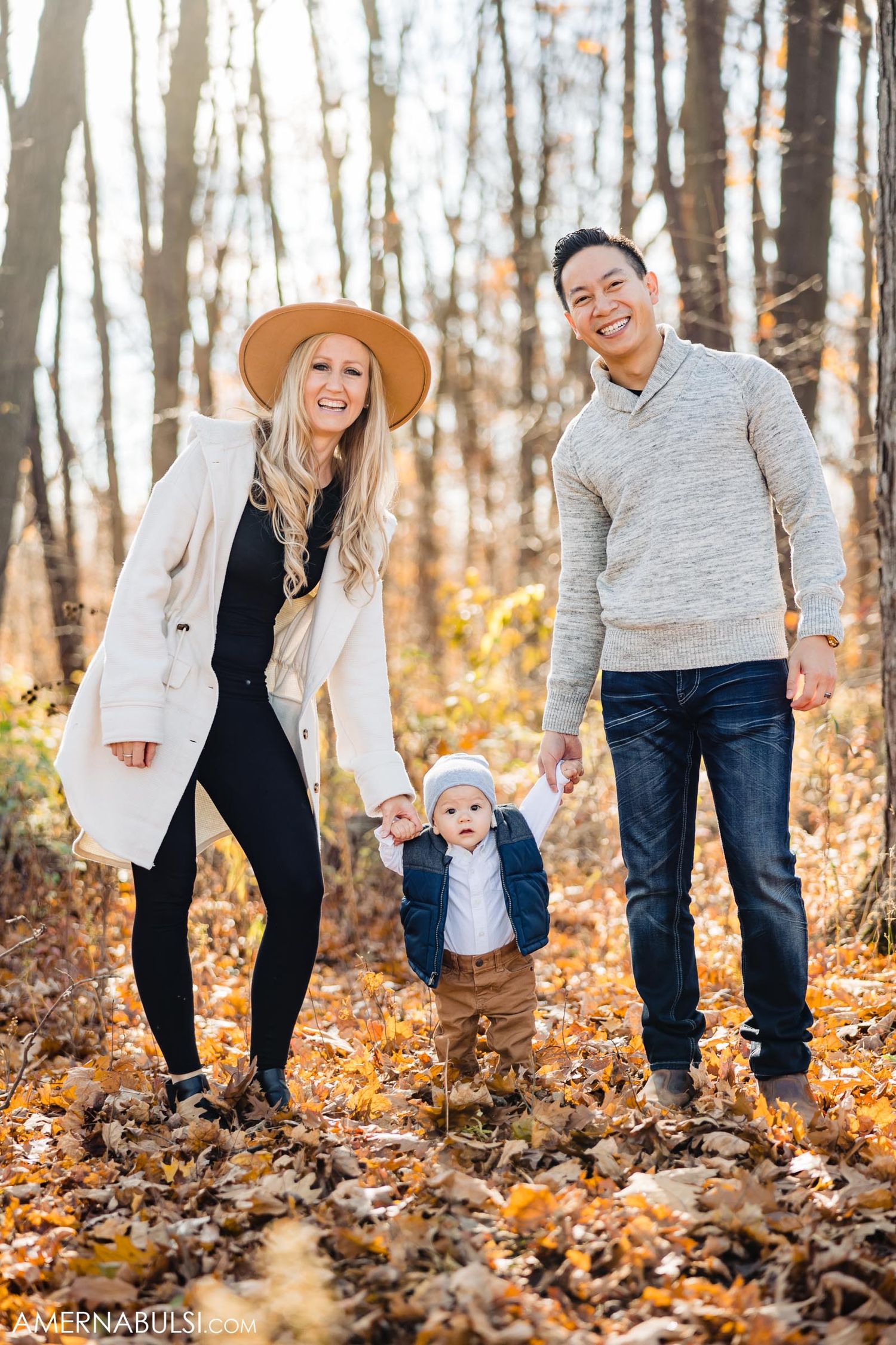 Happy family poses together in autumn forest surrounded by golden leaves.
