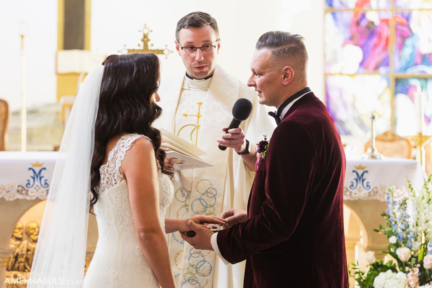 Wedding ceremony in progress with couple and officiant at decorated church altar.