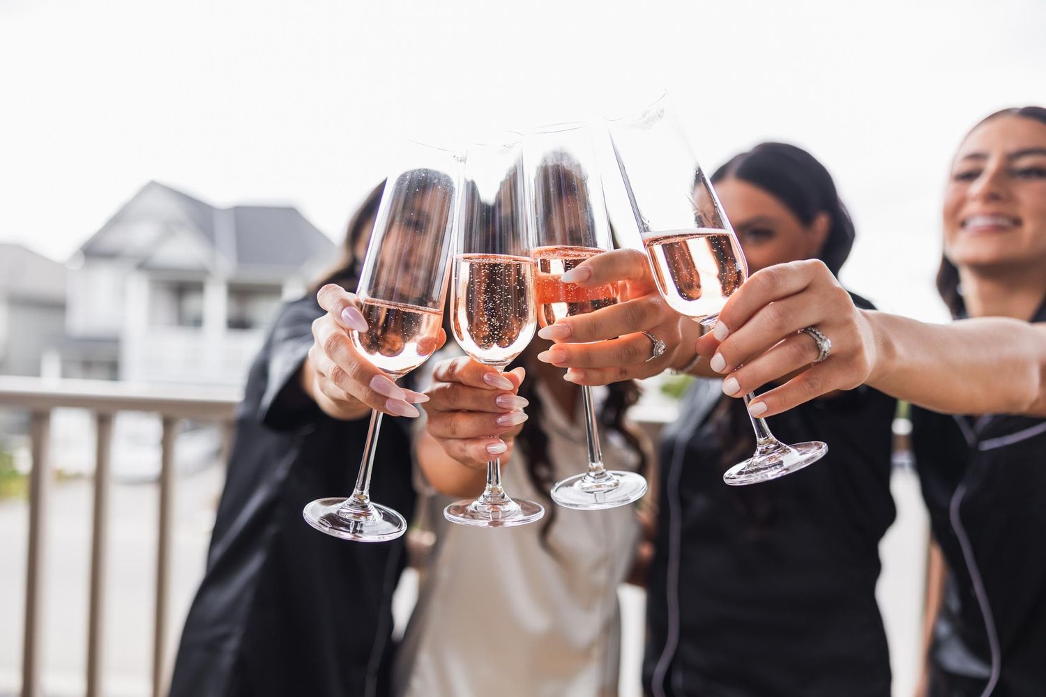 A group toasts with champagne glasses while celebrating on an outdoor balcony.