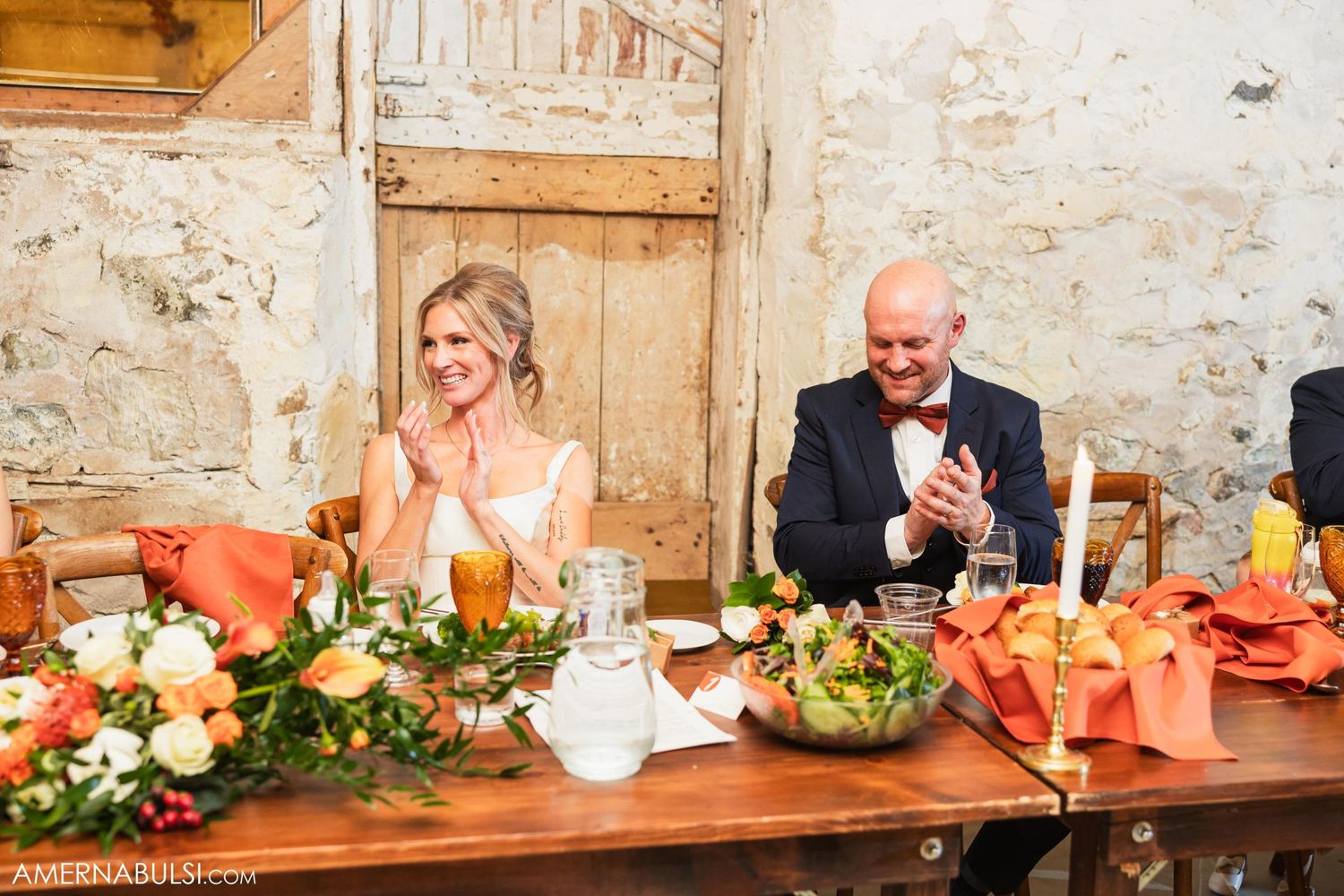 Candid moment at the wedding reception head table with colorful floral decorations.