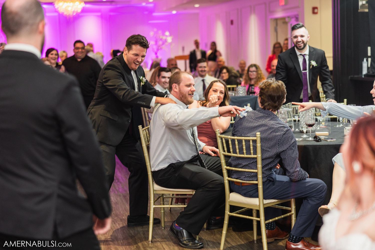 Wedding guests engaged in lively celebration at reception dinner tables.