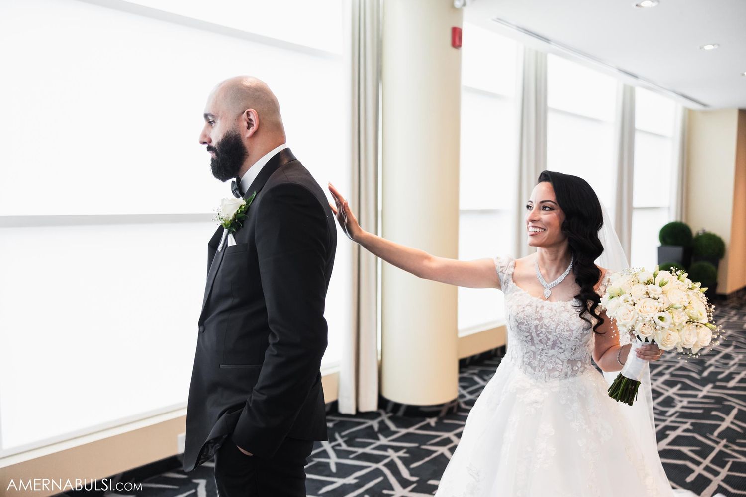Playful first look moment between newlyweds in modern indoor setting.