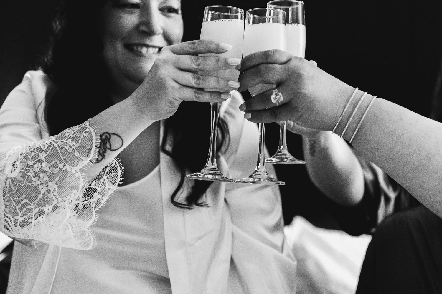 Black and white image of champagne glasses clinking in celebration.