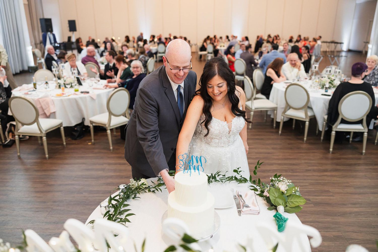 A couple prepares to cut their wedding cake at an elegant reception with floral decorations.